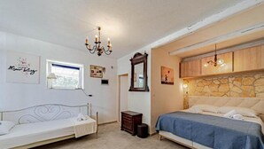Une chambre avec deux lits, un lustre, un mur en pierre et une fenêtre.