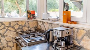 Une cuisine équipée d’une cuisinière à gaz, d’une machine à café et d’une fenêtre donnant sur les arbres.