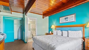 Una camera da letto con un letto grande, soffitto in legno, pareti color acquamarina e una cassettiera in legno.
