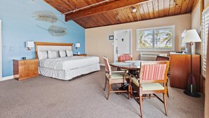 Quarto com cama, cômoda e escrivaninha com cadeiras.