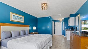 Quarto com uma cama grande, mesa de cabeceira, cômoda e vista para o exterior.