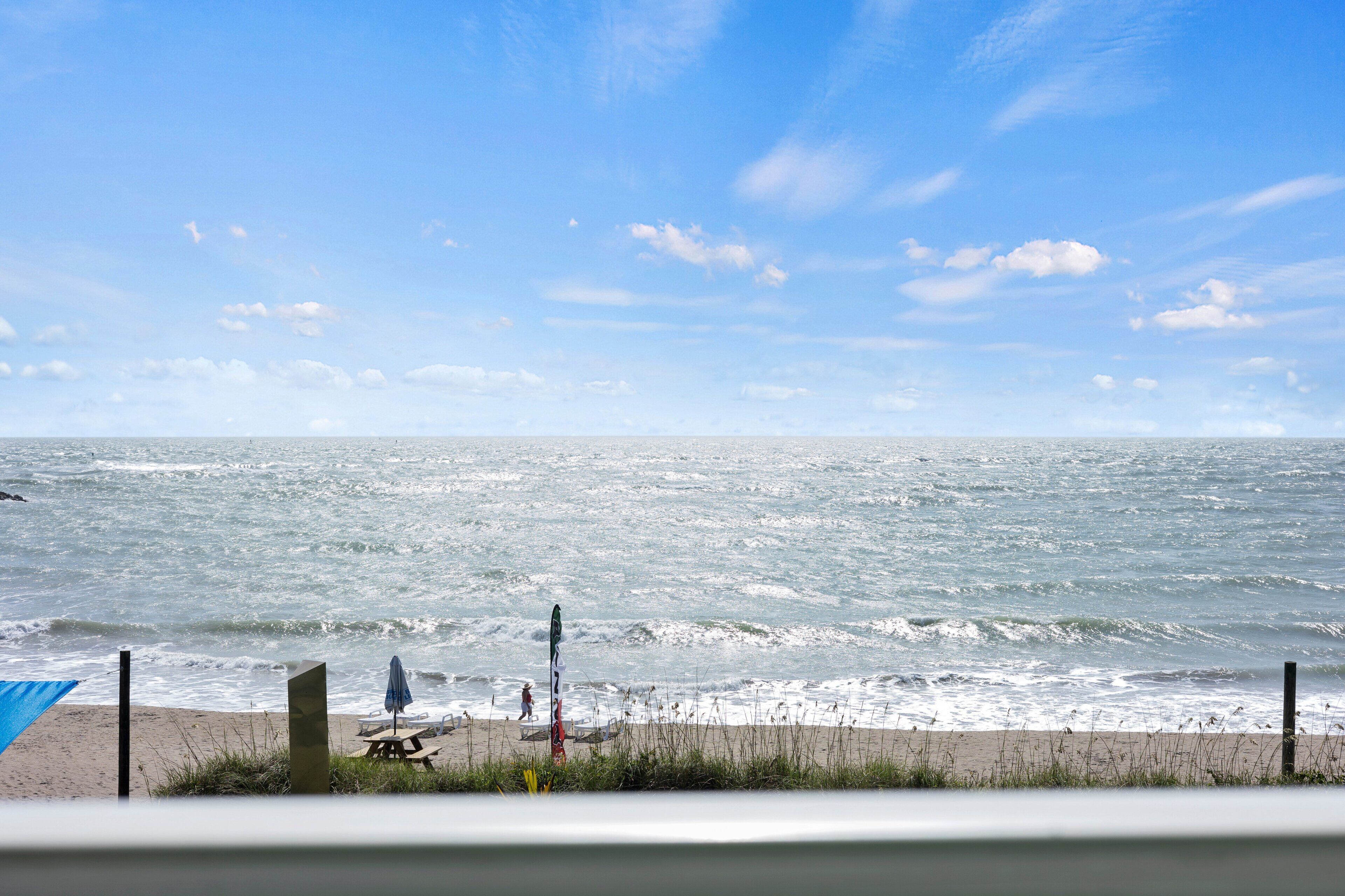 A beach with a sandy shore, a picnic table, and a blue umbrella.