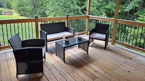 Eine Holzterrasse mit Korbmöbeln und einem Glastisch.