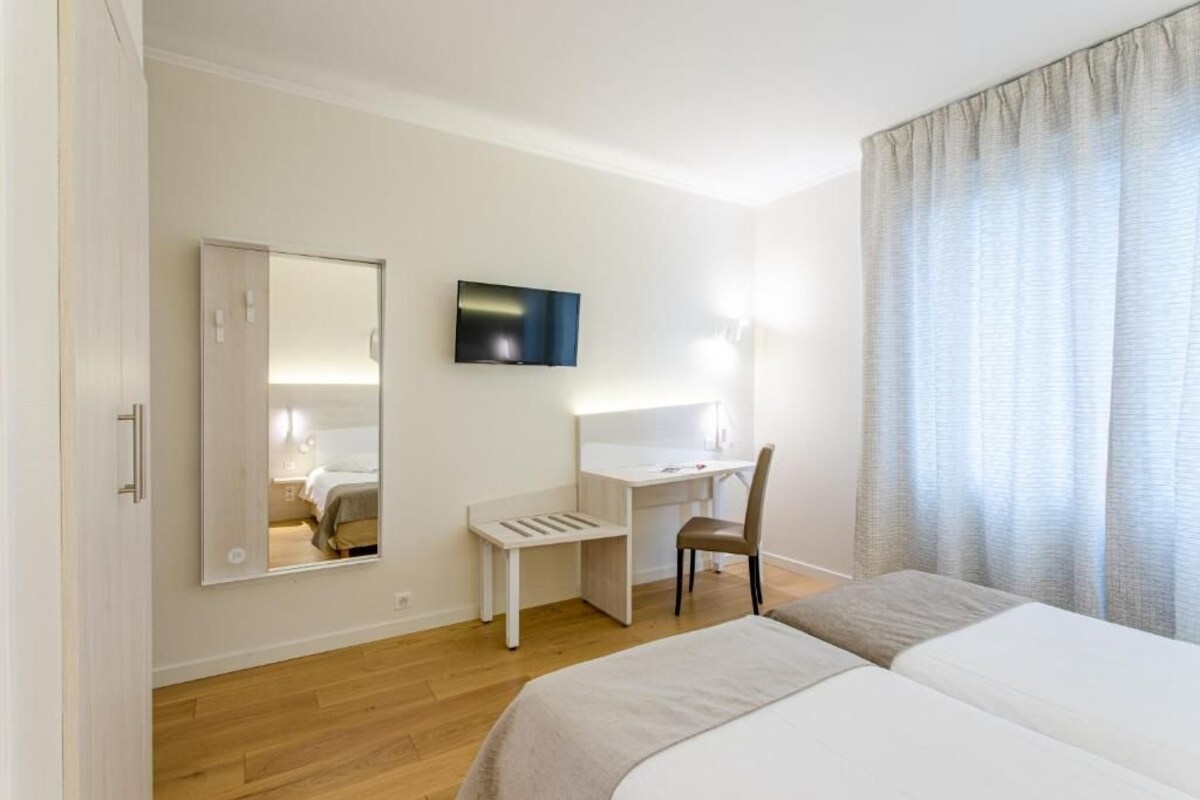 Een hotelkamer met een bed, een bureau, een stoel, een televisie en een spiegel.
