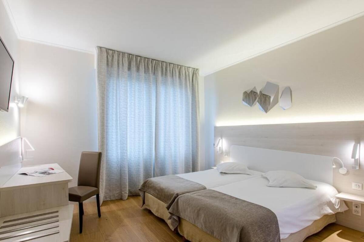 Une chambre d’hôtel avec un lit, un bureau, une chaise et un téléviseur.
