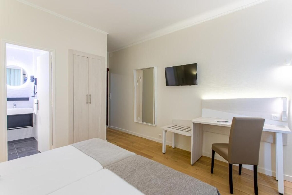 Une chambre d’hôtel avec un lit, un bureau, une chaise, une télévision et un miroir.