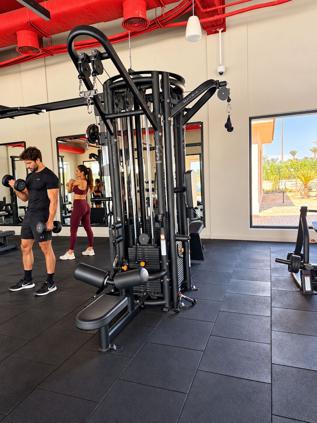 Ein Fitnessraum mit Trainingsgeräten, einem großen Fenster und Blick ins Freie.