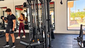 Ein Fitnessraum mit Trainingsgeräten, einem großen Fenster und Blick ins Freie.