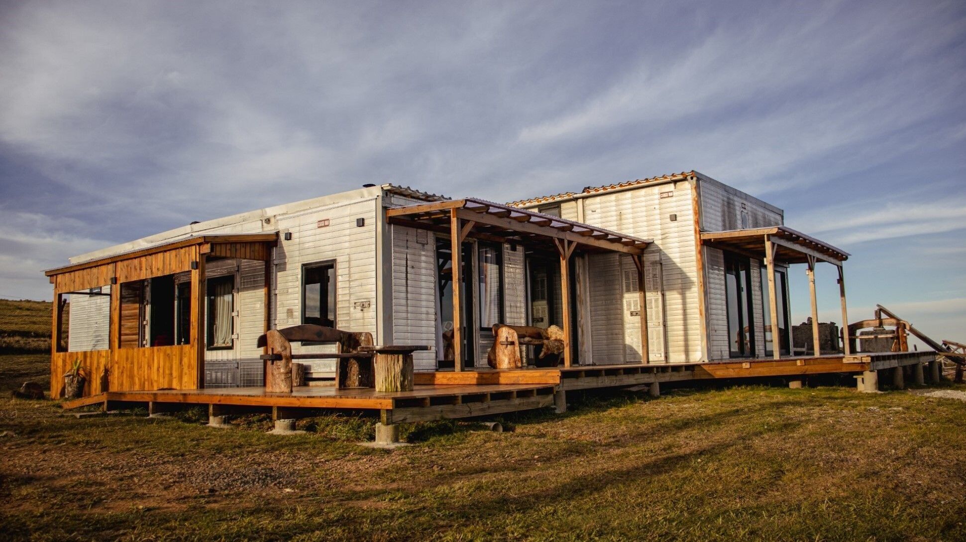 A rustic cabin with a wooden deck, large windows, and a covered porch.