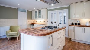 A modern kitchen with a central island, white cabinetry, and a green armchair.