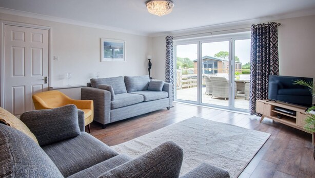 A modern living room with a grey sofa set, a yellow armchair, and a flat-screen TV.