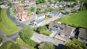 An aerial view of a residential area with houses, roads, and a coastline in the background.