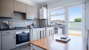 A modern kitchen with a Bosch oven, a wooden countertop, and a view of the backyard through a glass door.