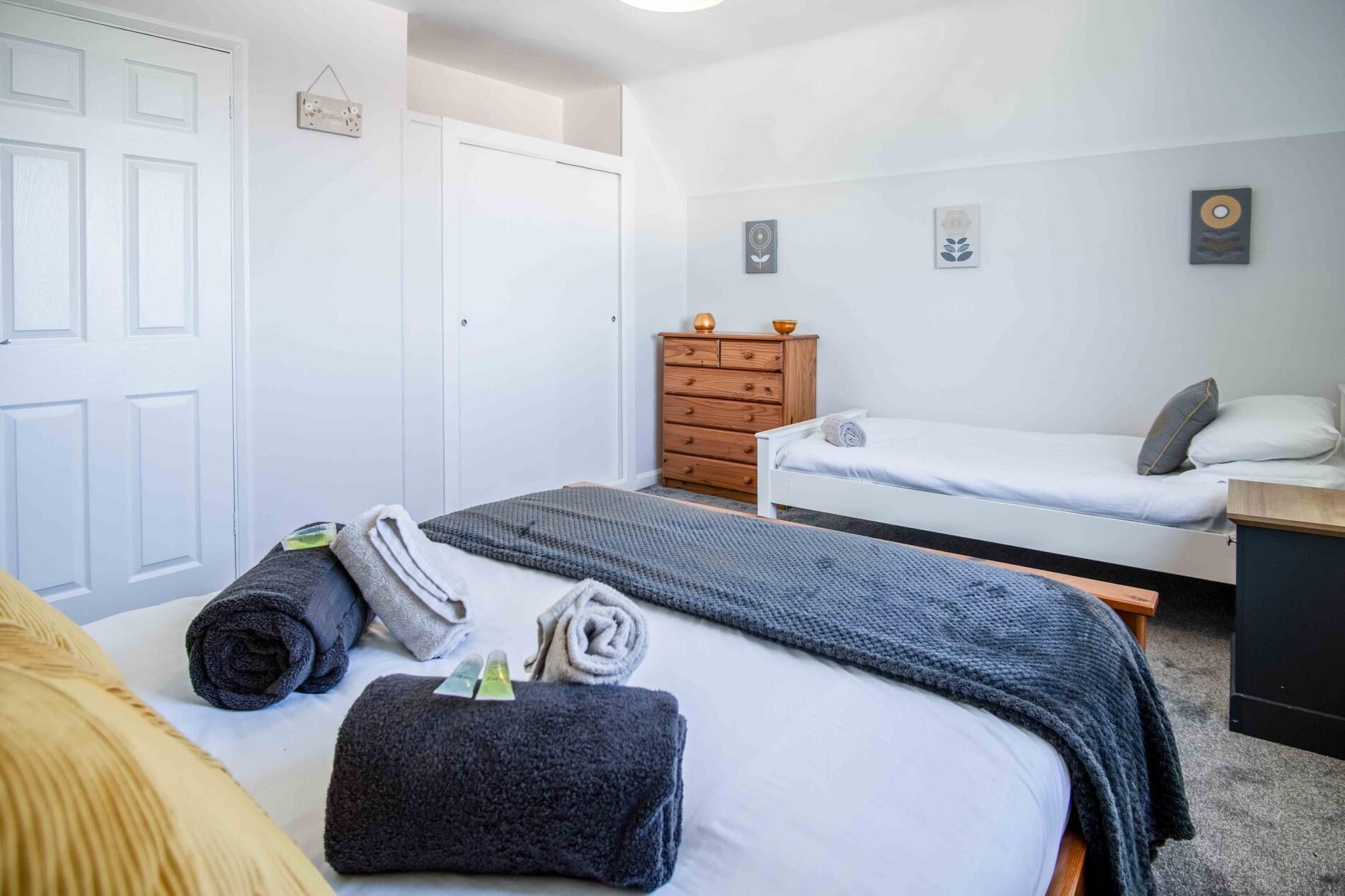 Een slaapkamer met twee bedden, een dressoir en een klein bureau.