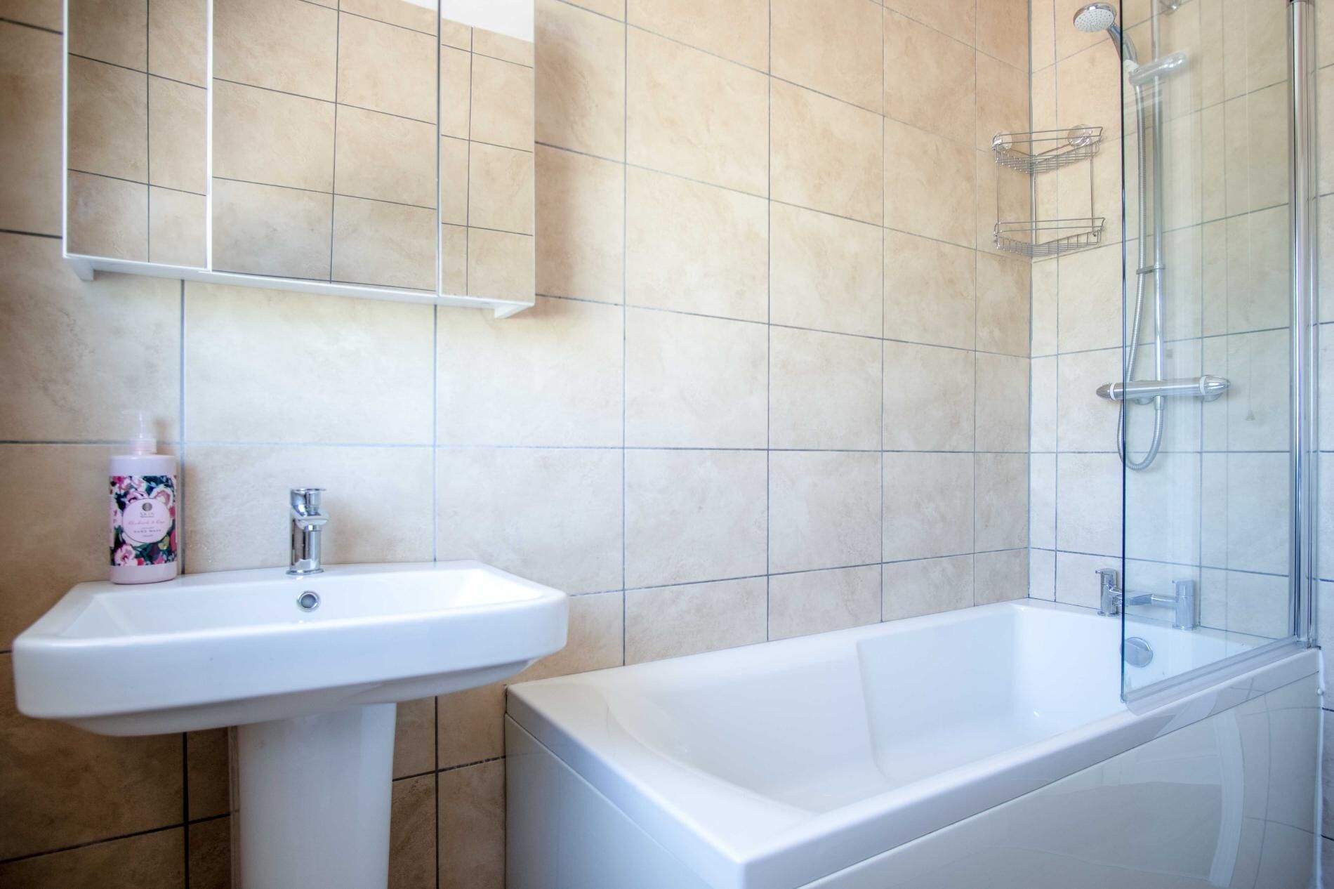 Un baño con lavamanos blanco, bañera y cabina de ducha de vidrio.