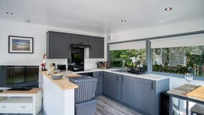Una cucina moderna con mobili grigi, un forno a microonde integrato e un'ampia finestra con vista sul verde.