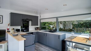 Una cucina moderna con mobili grigi, un piano di lavoro in legno e vista sul verde.