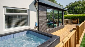 Area esterna moderna con vasca idromassaggio, un decking in legno, un patio con vetrate e un muro esterno bianco.