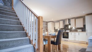 A modern kitchen with white cabinets, a built-in oven, and a dining area with a wooden table and chairs.
