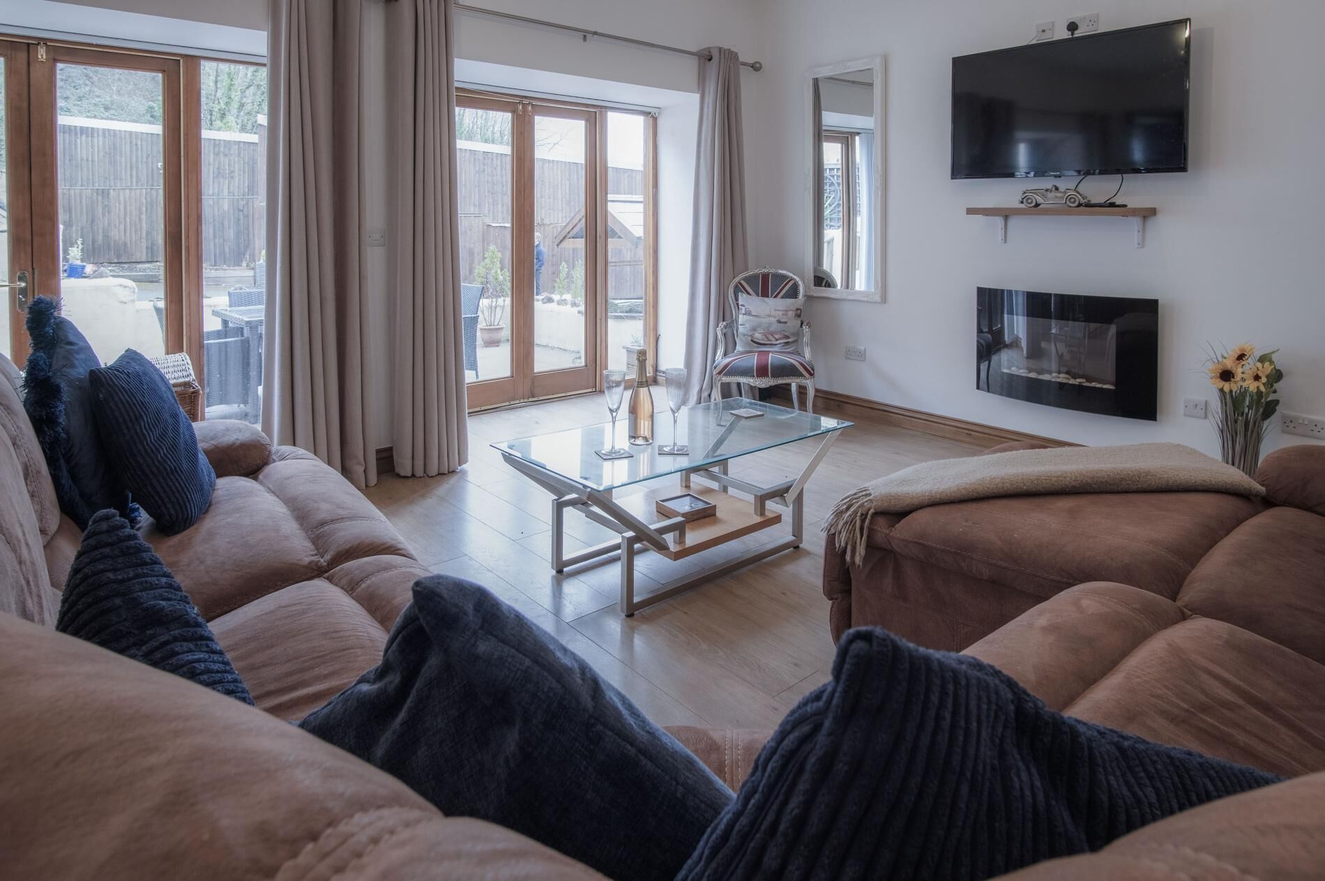 Una sala de estar con una mesa de centro de vidrio, un sofá y un televisor montado en la pared.