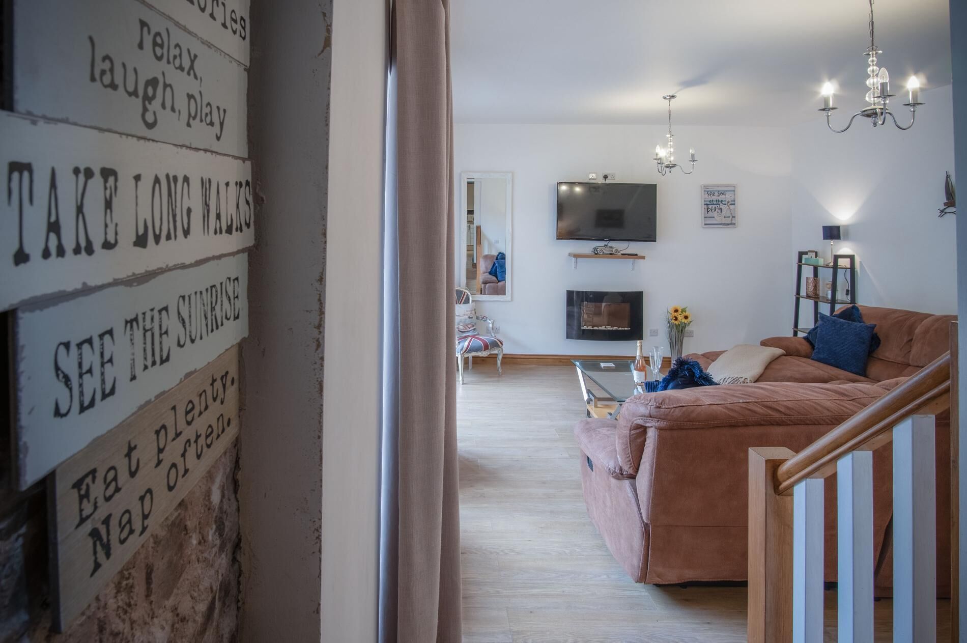 Un salon comprenant un canapé, un téléviseur, une cheminée et un mur orné d’affiches inspirantes.