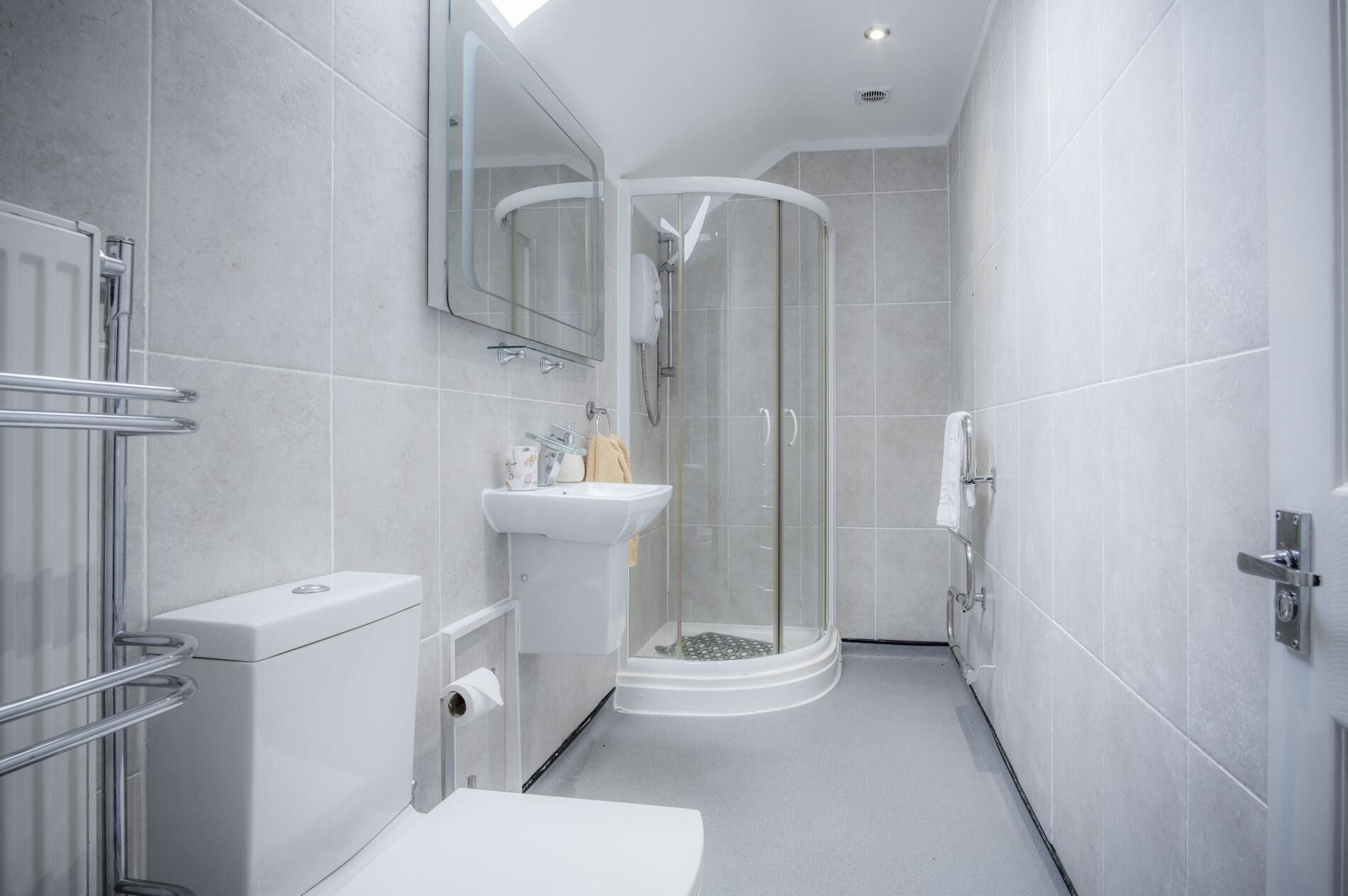 A modern bathroom with a glass shower enclosure, a white sink, and a toilet.
