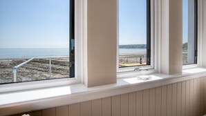 A room with a view of the beach and sea through large windows. - Waterfront 1 - 1 Bedroom Apartment - Wisemans Bridge (Saundersfoot)