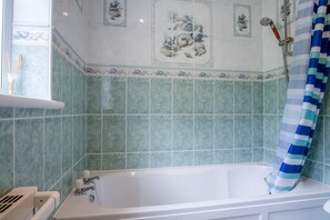 A bathroom with a bathtub, green tiles, and a shower curtain. - Audreys - 3 Bed Holiday Home - Manorbier (Tenby)