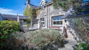 A stone house with a garden, a wooden bench, and a table. - Fern Cottage - 2 Bedroom Cottage - St. Florence (Tenby)