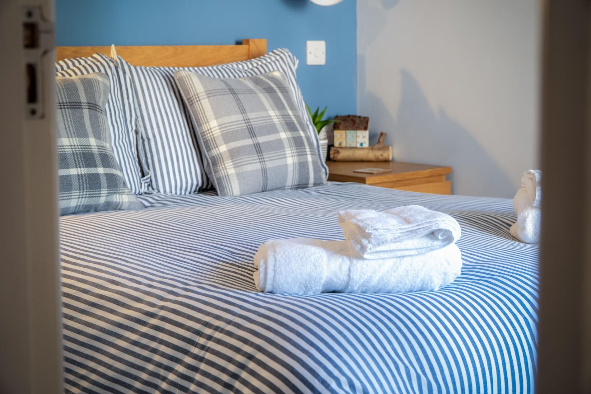 A neatly made bed with striped bedding and a folded towel on it.