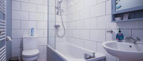 A bathroom with white tiles, a bathtub, a toilet, a sink, and a shower.