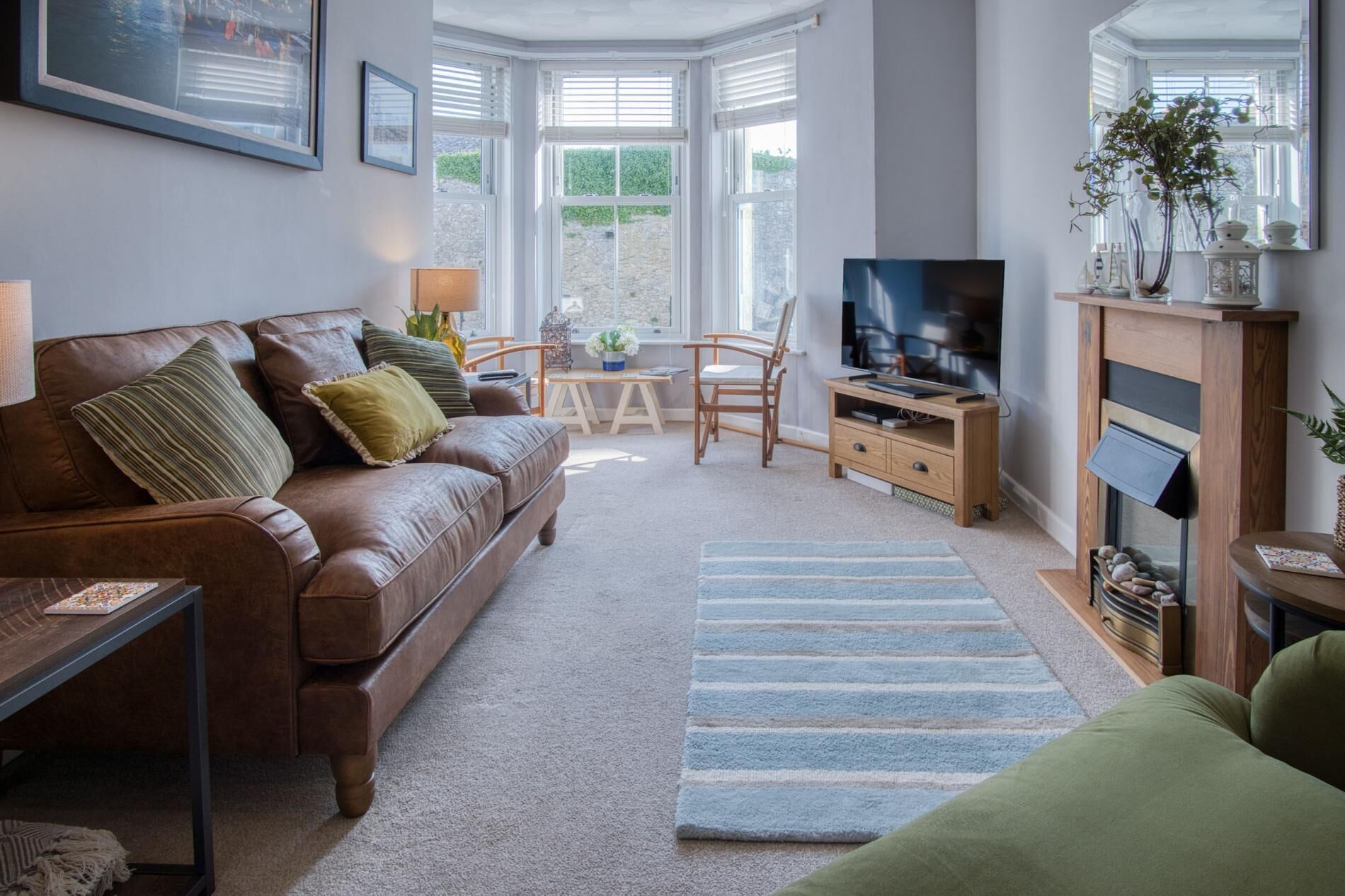 Ein gemütliches Wohnzimmer mit einer Ledersofa, einem Couchtisch aus Holz, einer TV-Konsole und einem Kamin.