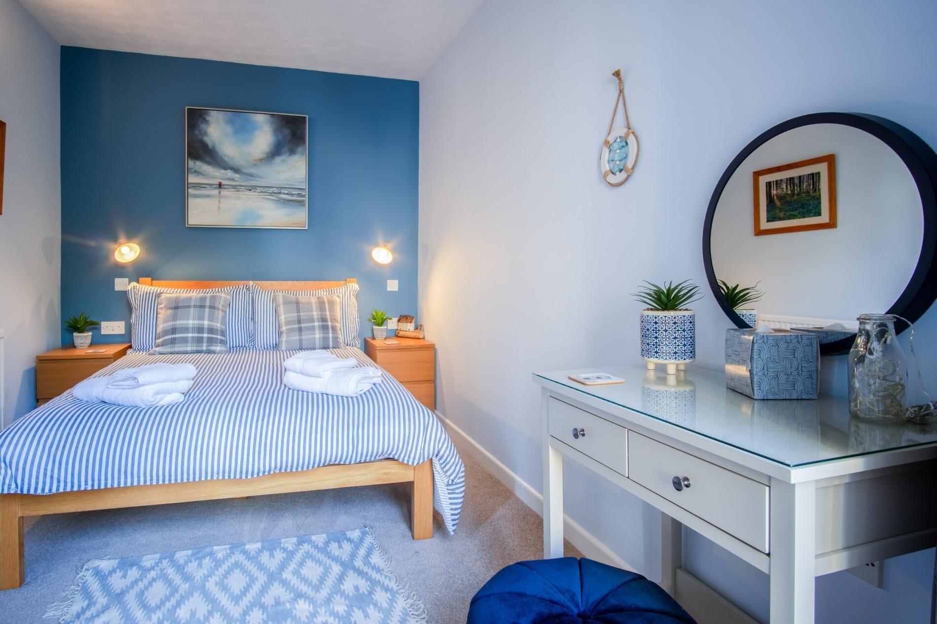 Een slaapkamer met een bed, nachtkastjes, een kaptafel, een spiegel en decoratie aan de muur.