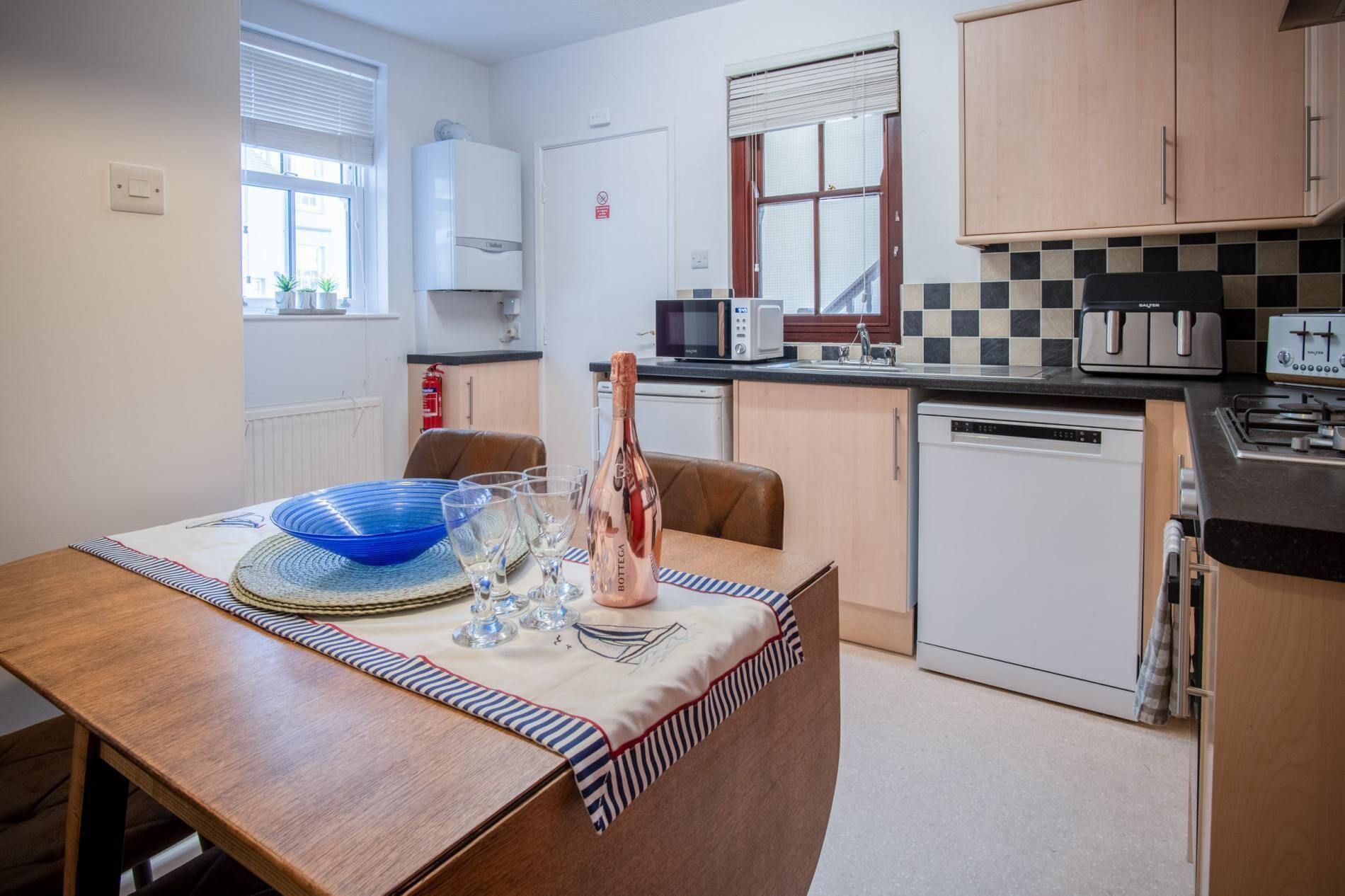 A compact kitchen with a dining area, featuring a microwave, toaster, and dishwasher.