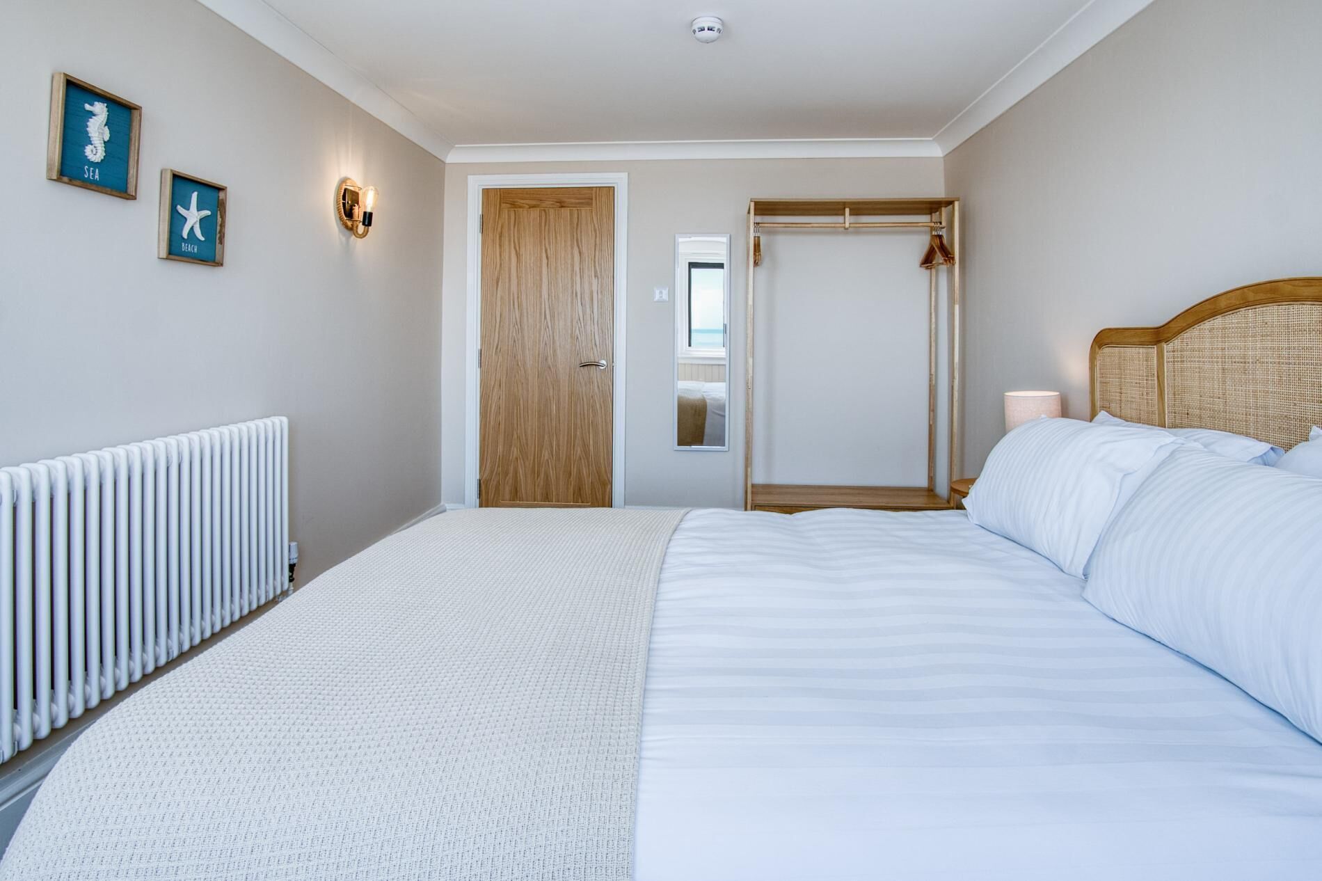 Ein Schlafzimmer mit einem Bett, einem Heizkörper, einer Holztür und Wandbildern.
