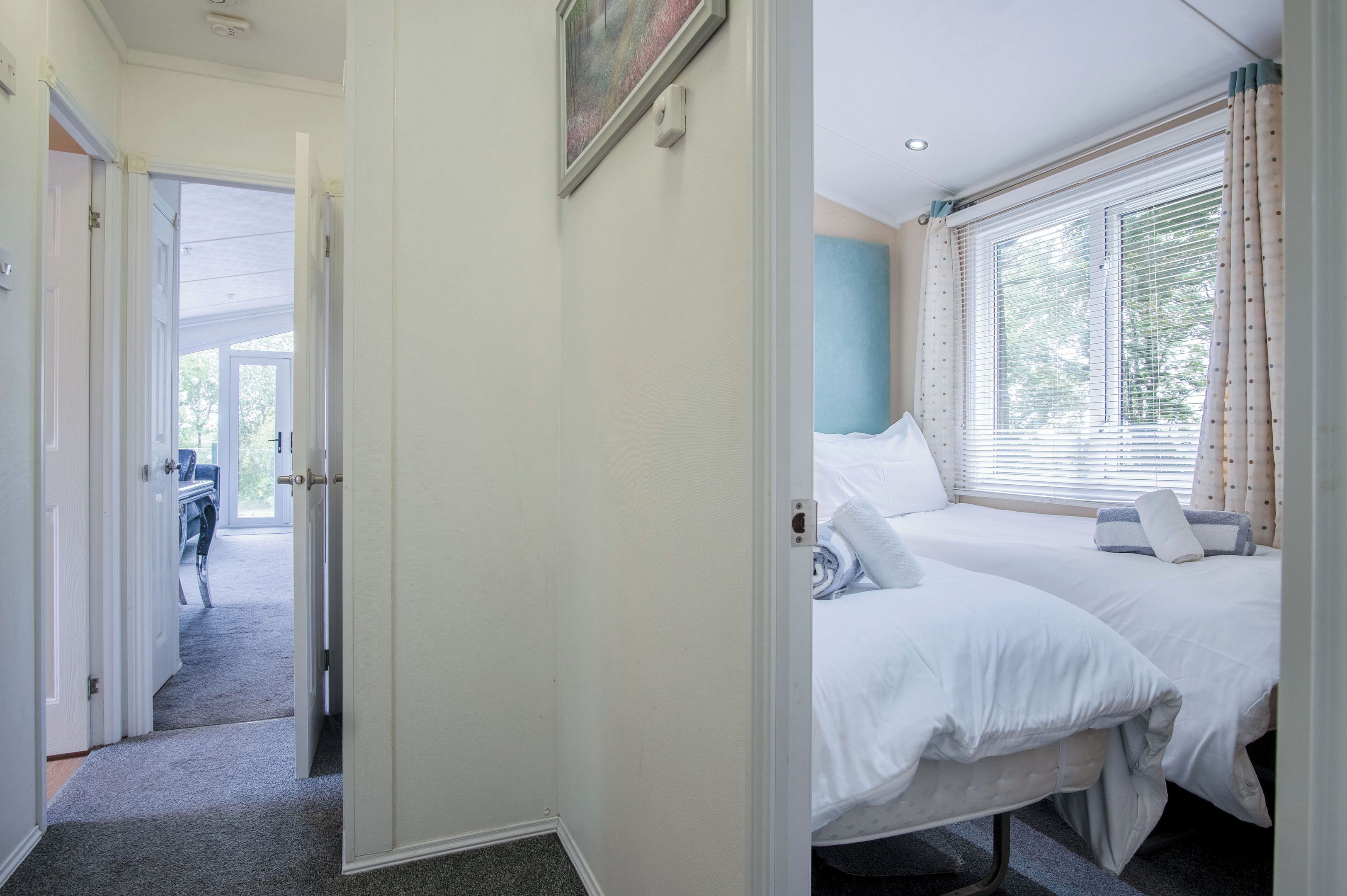 A hotel room with two beds, a desk, and a window with curtains.