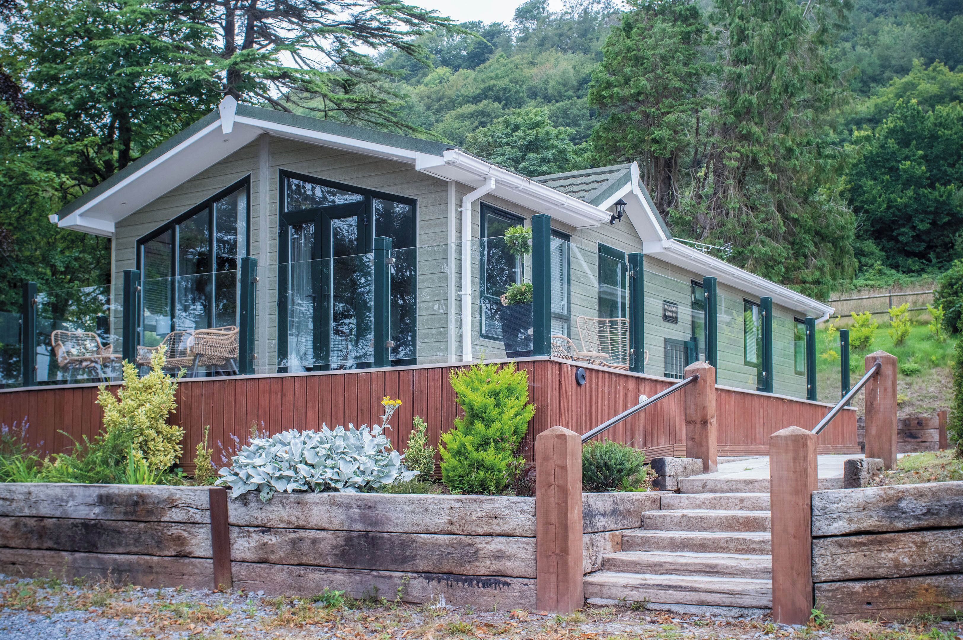 A modern house with large windows, a wooden deck, and a stone staircase.