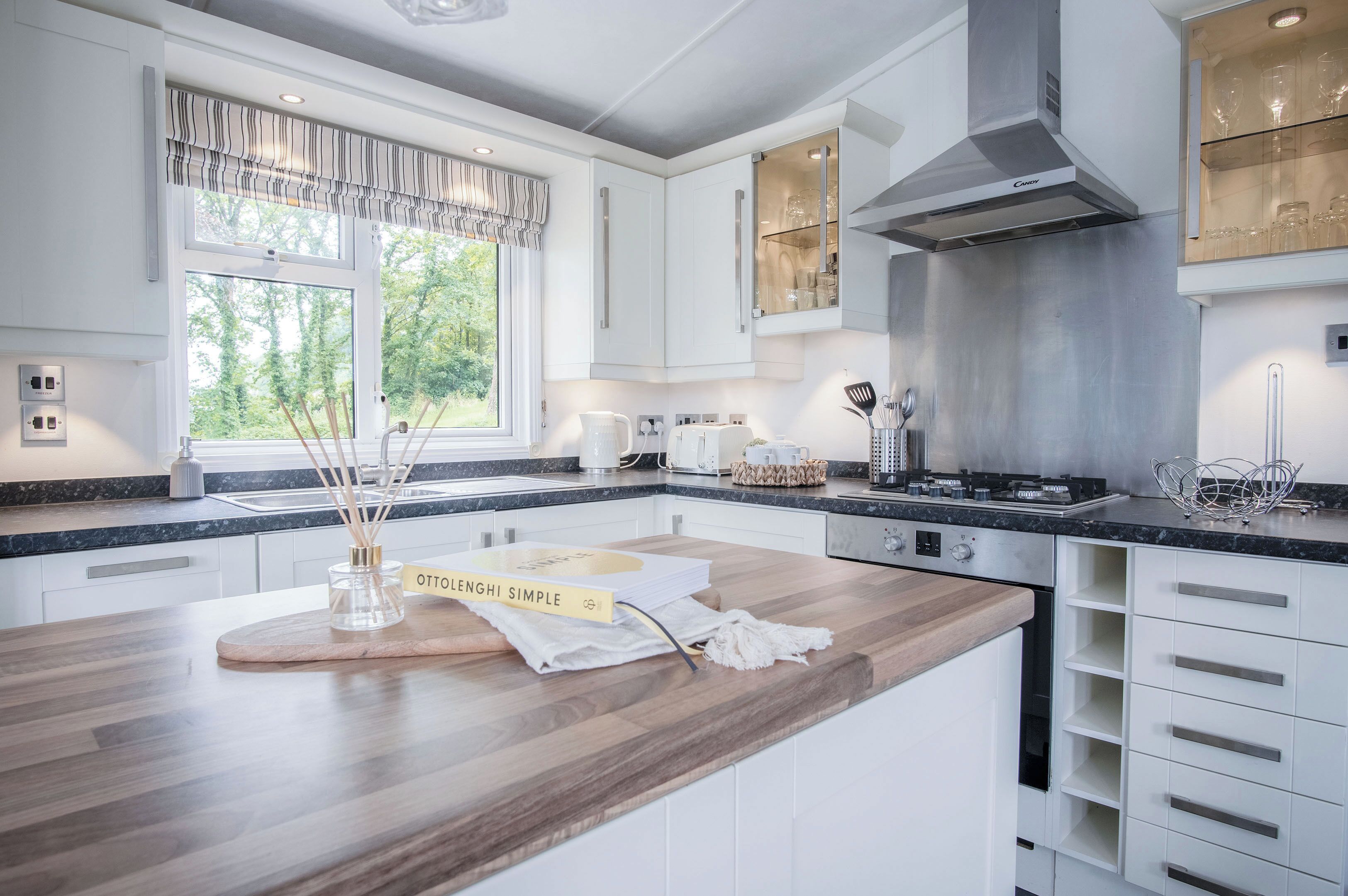 A modern kitchen with white cabinetry, a wooden countertop, and a built-in stove.