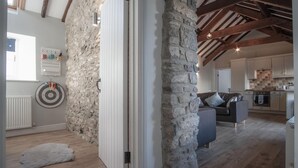 Een ruime woonkamer met zichtbare stenen muren, een moderne keuken en een gezellige zithoek.