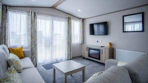 Ein modernes Wohnzimmer mit einer Couch, einem Couchtisch, einem Flachbildfernseher und einem Kamin.