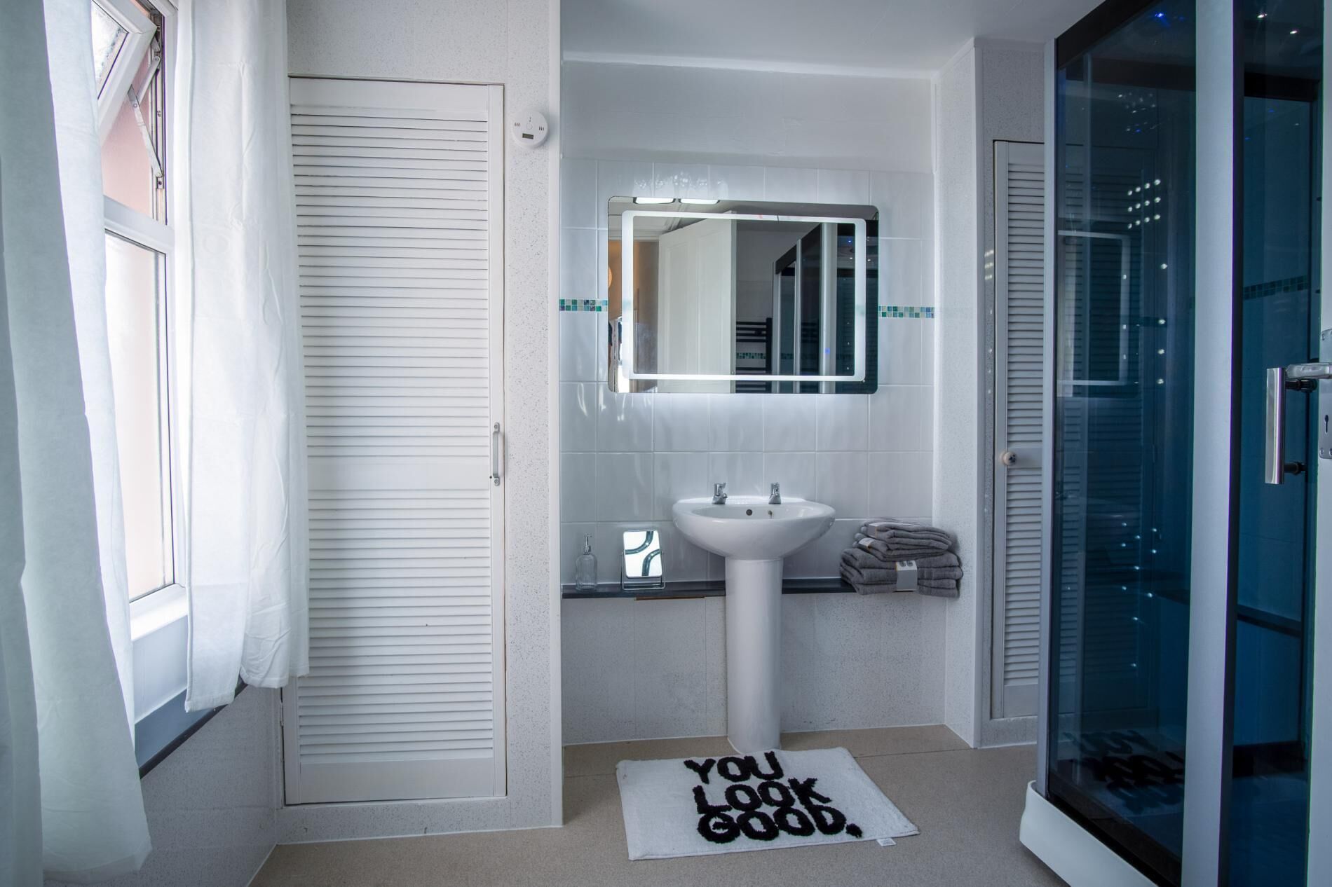 A bathroom with a white sink, a mirror, and a towel rack.