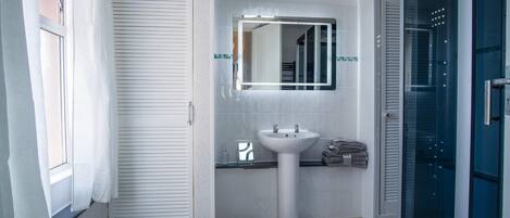A bathroom with a white sink, a mirror, and a towel rack.