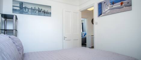 Ein Schlafzimmer mit einem Bett, einer Tür, einem Spiegel und zwei Wandbildern.