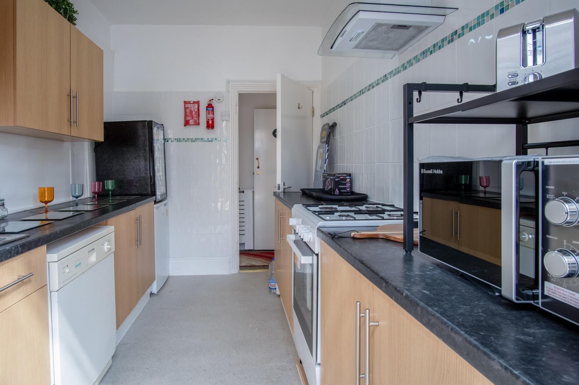 A modern kitchen with wooden cabinets, a black countertop, a gas stove, and a built-in oven.
