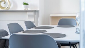A modern meeting room with a white table, grey chairs, and a small potted plant on a shelf. - Skyfall - 2 Bedroom Apartment - Milford Haven (Milford Haven)