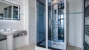 A modern bathroom with a glass-enclosed shower, a white sink, and a towel rack. - Skyfall - 2 Bedroom Apartment - Milford Haven (Milford Haven)