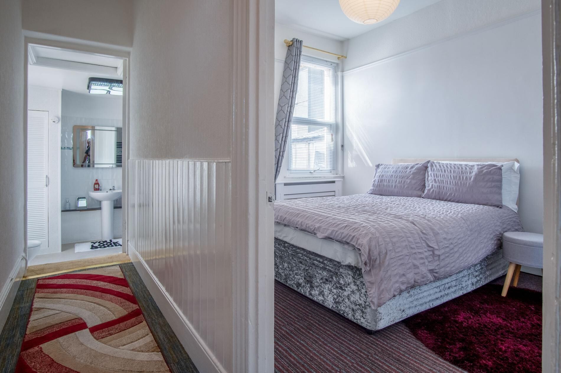 A bedroom with a bed, a window with curtains, a bedside table, and a nightstand.