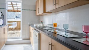 A modern kitchen with wooden cabinets, a black countertop, and a view to a patio area. - Skyfall - 2 Bedroom Apartment - Milford Haven (Milford Haven)