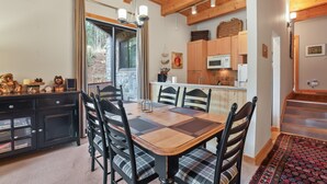 Un espace repas avec une table et des chaises en bois, une cuisine équipée d’appareils modernes et une vue sur l’extérieur.