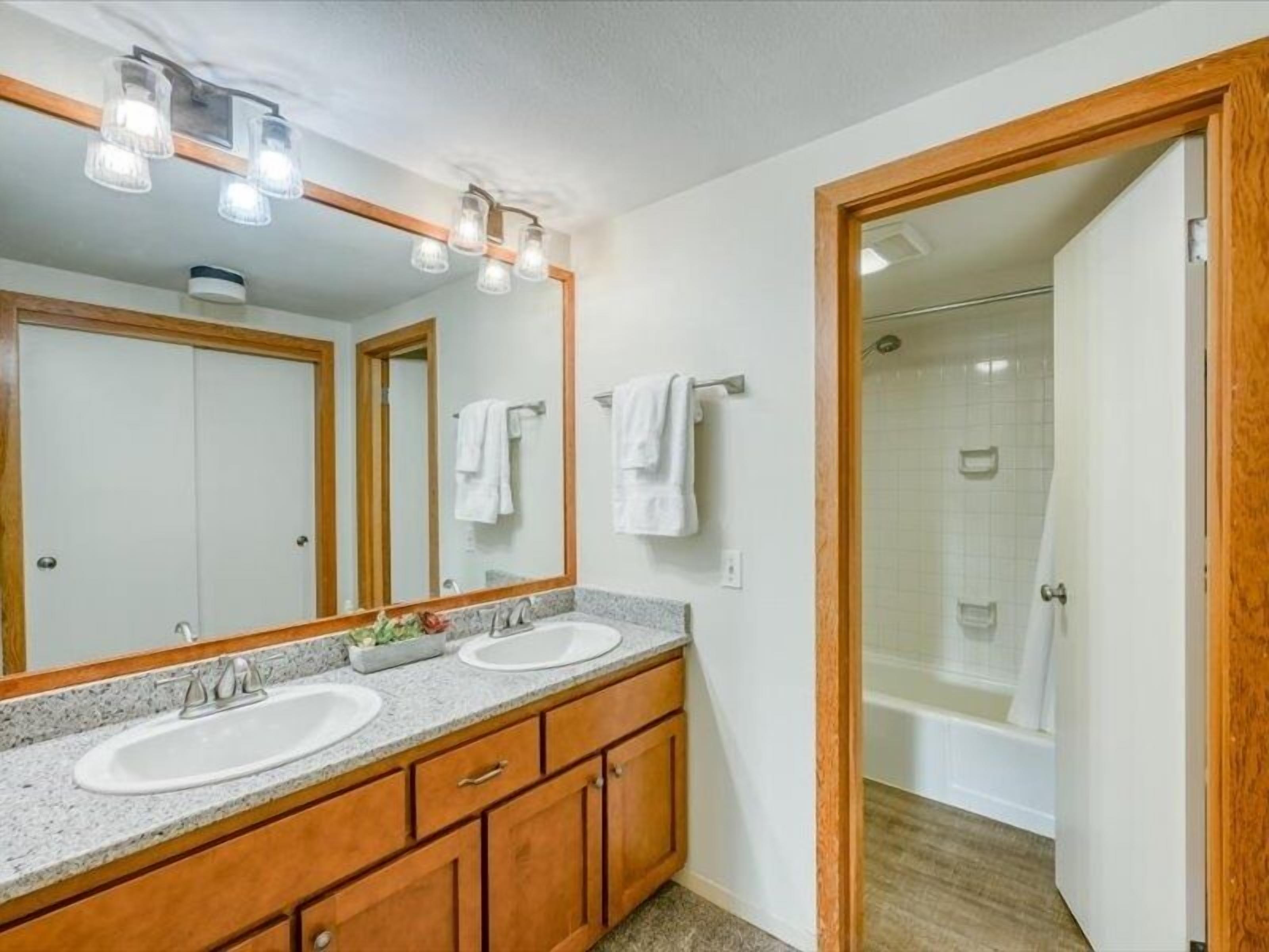 A bathroom with two sinks, a large mirror, and a shower area.